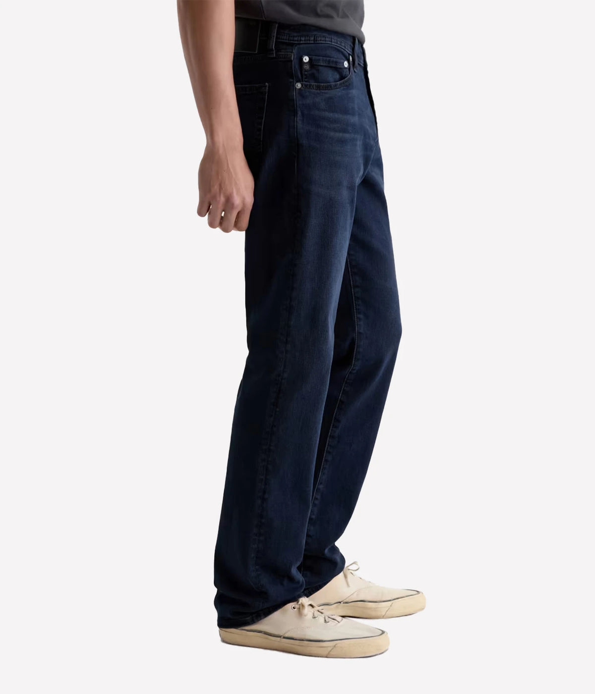 Man wearing AG Graduate Jean in Studio with cream sneakers, side view