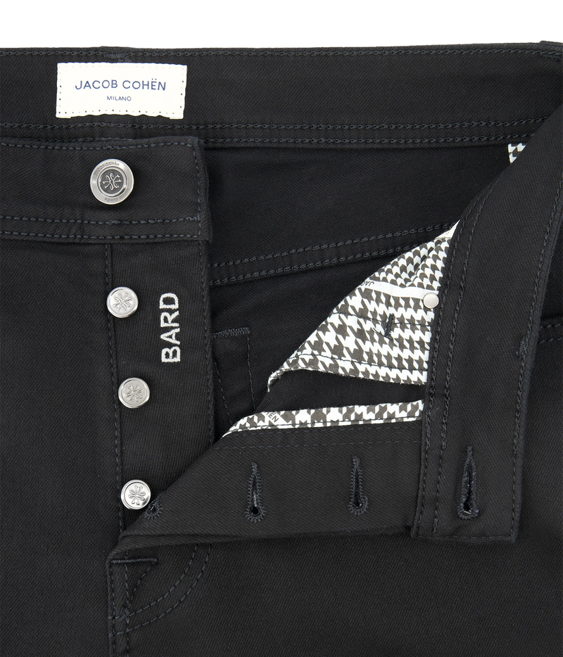 Close-up of black jeans by Jacob Cohen, showing the waistband, button closure, side pocket with 'BARD' embroidery, and a patterned inner lining.