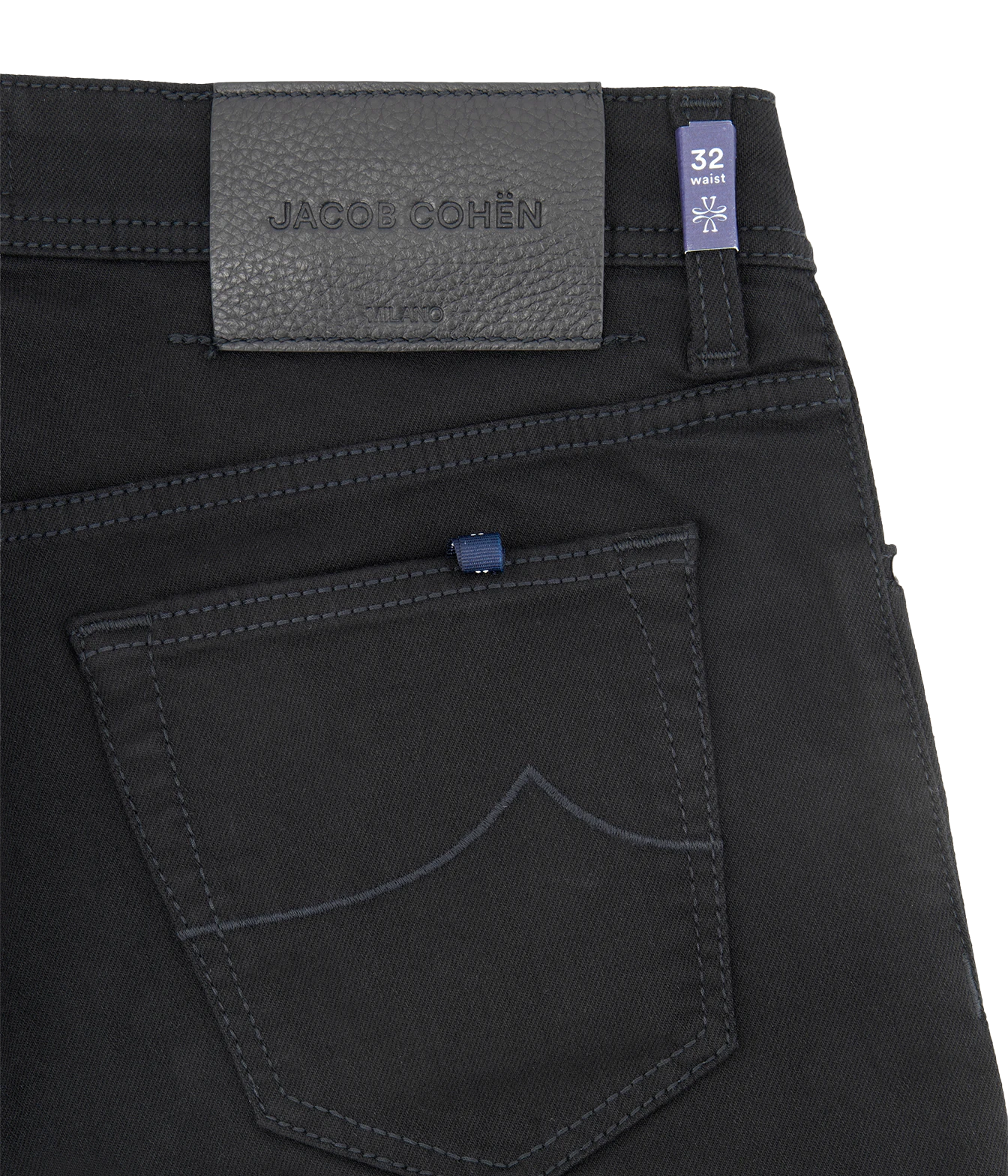Close-up of the back waistband and pocket of black denim jeans by Jacobs Cohen, showing a dark gray leather brand patch, a blue size tag, and contrast stitching.