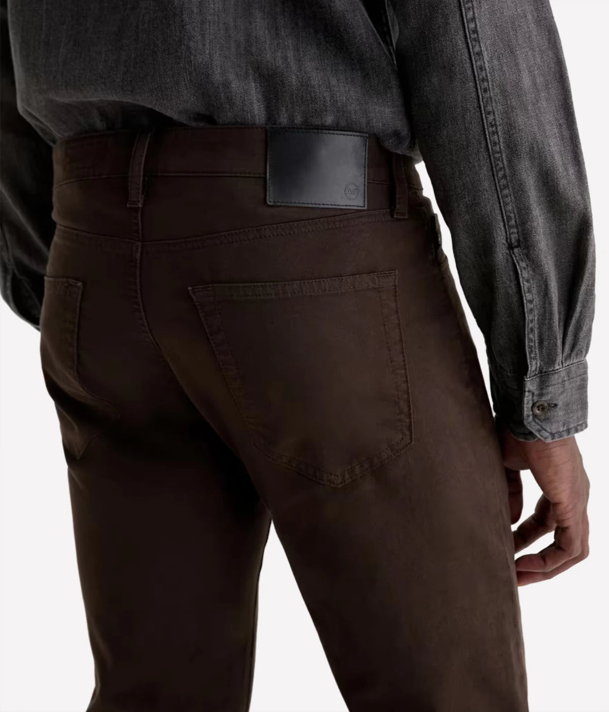Close-up back view of a person wearing dark brown pants and a dark charcoal gray long-sleeve shirt, showing the back pocket and waistband.