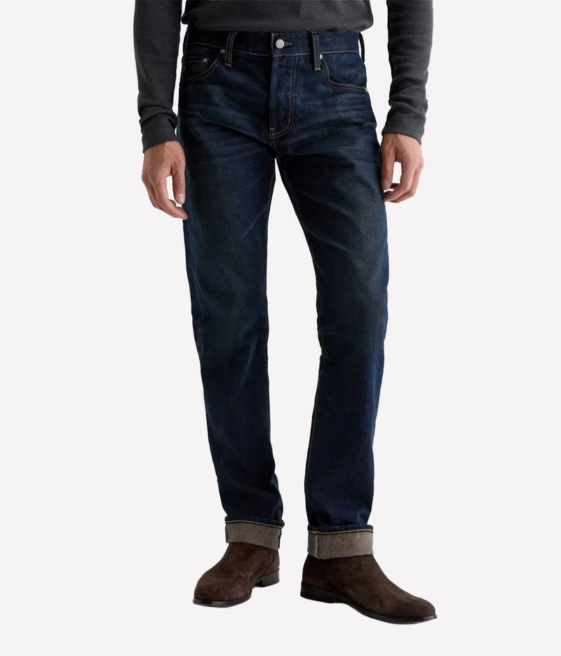 Man wearing AG Tellis Selvage Jean in 3 Years Out Of The Blue with a grey knit and brown suede boots, front view