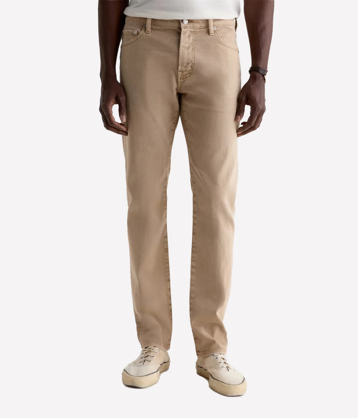 A person wearing straight-leg beige jeans with a white t-shirt and off-white sneakers, shown from the waist down against a light gray studio background.