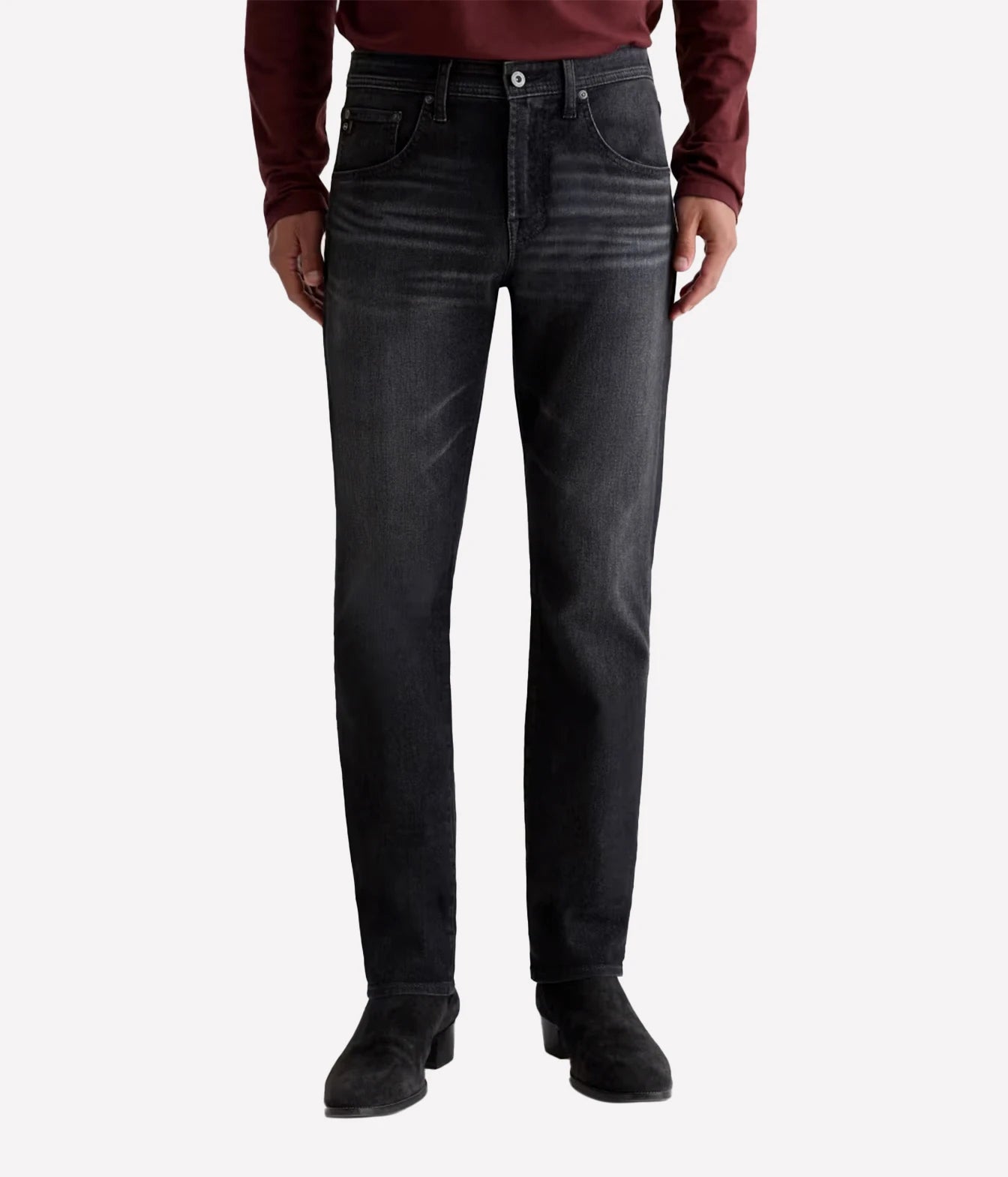A person wearing dark charcoal gray slim-fit jeans, a burgundy long-sleeve shirt, and black boots, shown from the waist down against a light gray studio background.