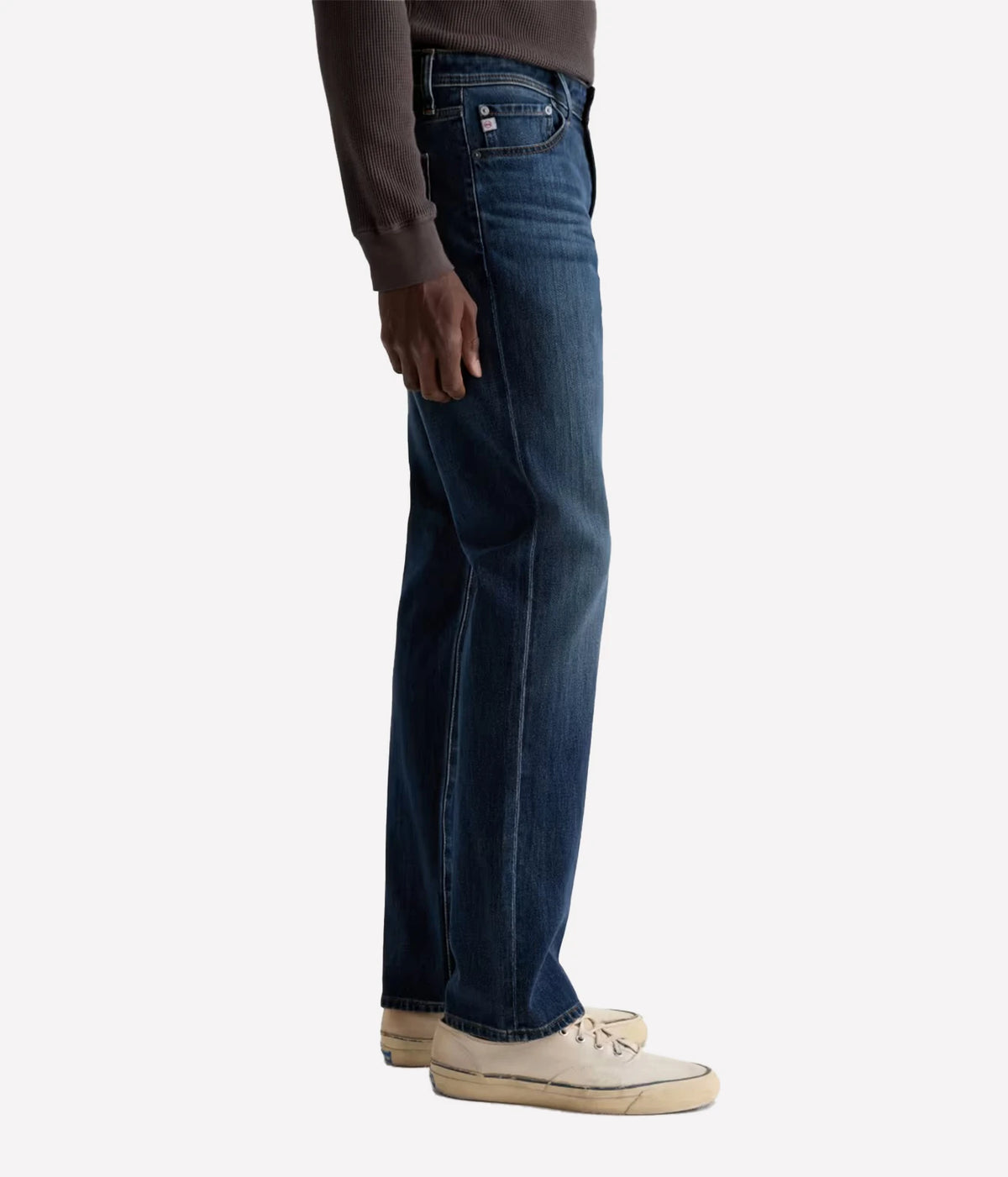 Person wearing  dark blue denim jeans with a white background
