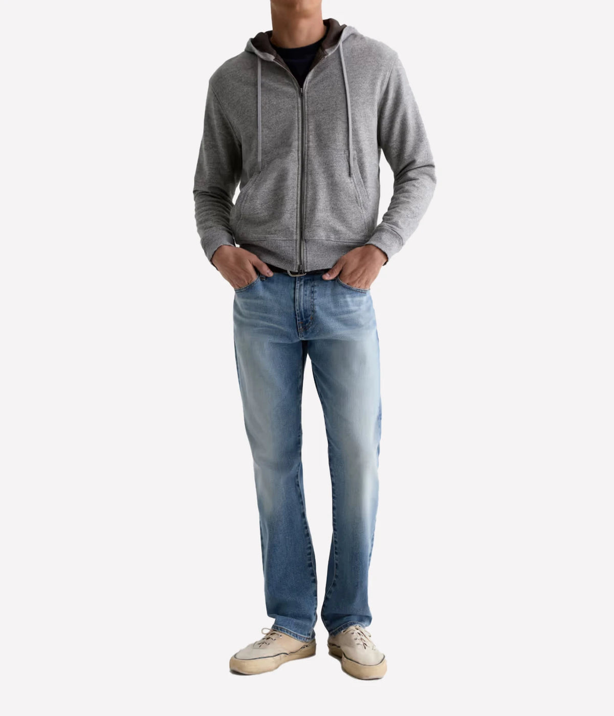 Man wearing AG Everett Jean in Watkins with a grey zip-up knit and off-white sneakers, front view