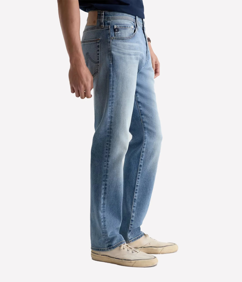 Man wearing AG Everett Jean in Watkins with off-white sneakers, side view