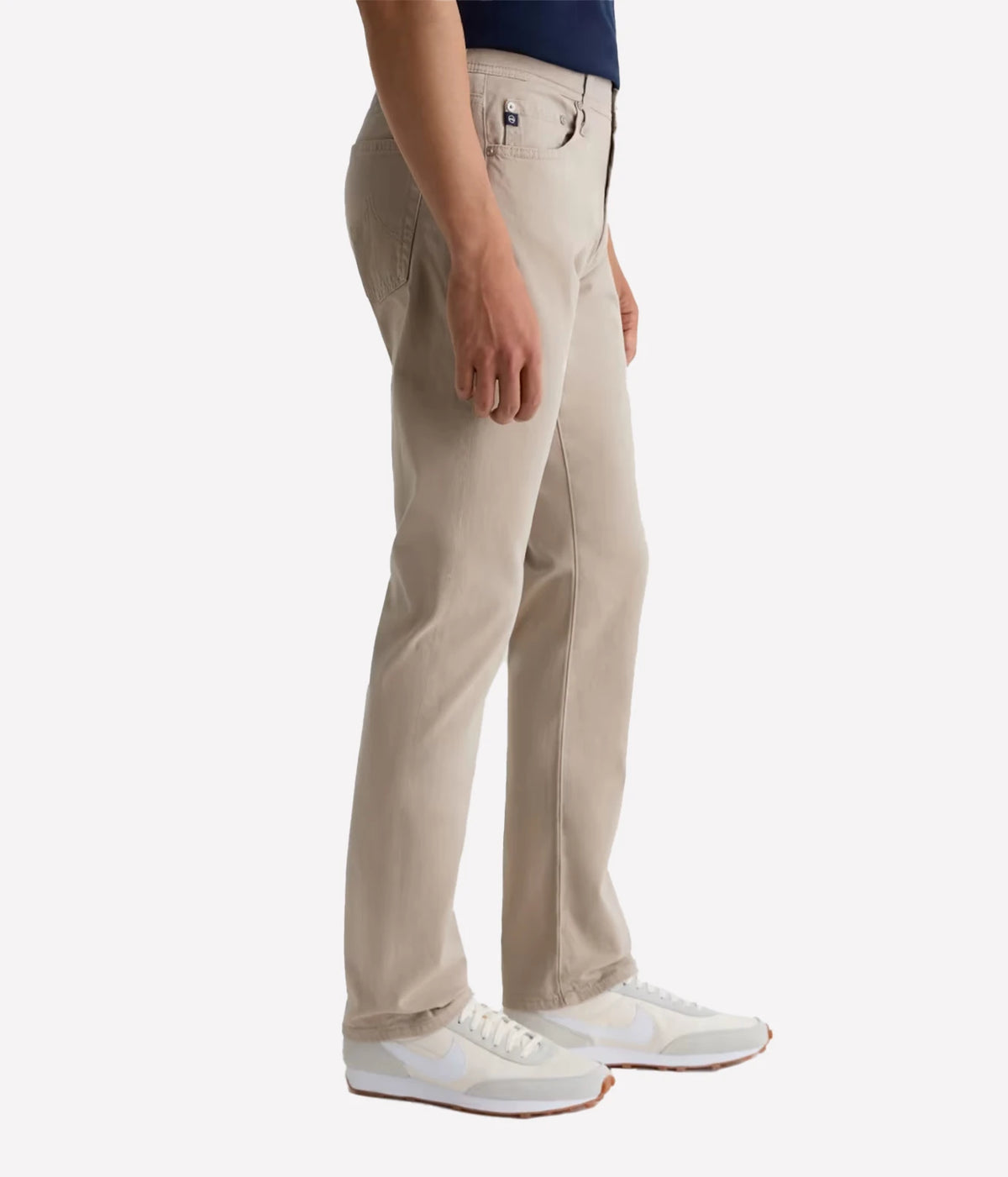 Man wearing AG Everett SUD Pant in Desert Stone with white sneakers, side view
