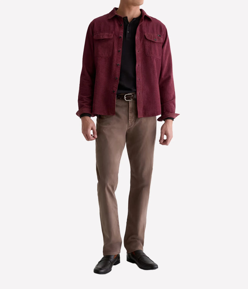 Man wearing AG Everett SUD Pant in Sulfur Taupe Grey with a burgundy jacket, black top and black shoes, front view