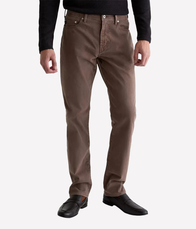 Man wearing AG Everett SUD Pant in Sulfur Taupe Grey with a black long-sleeve top and black shoes, front view