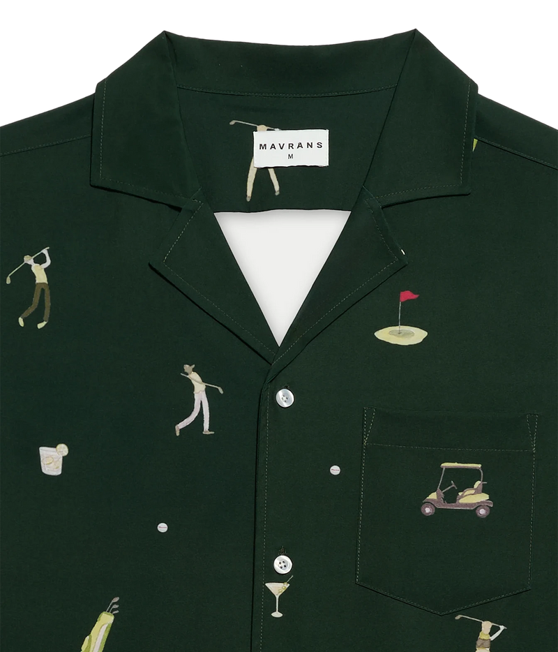 A dark forest green short-sleeve button-up shirt by Mavrans, featuring a golf-themed print with illustrated golfers, a golf cart, a flagstick, and golf balls. The shirt is displayed flat against a clean white background.