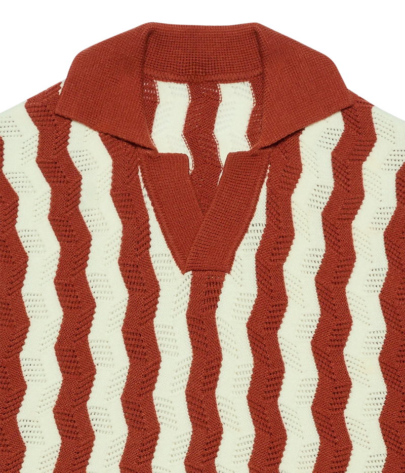 Close-up of a knit polo-style sweater with vertical wavy stripes in rust red and off-white, featuring a solid rust red collar and V-neck placket.