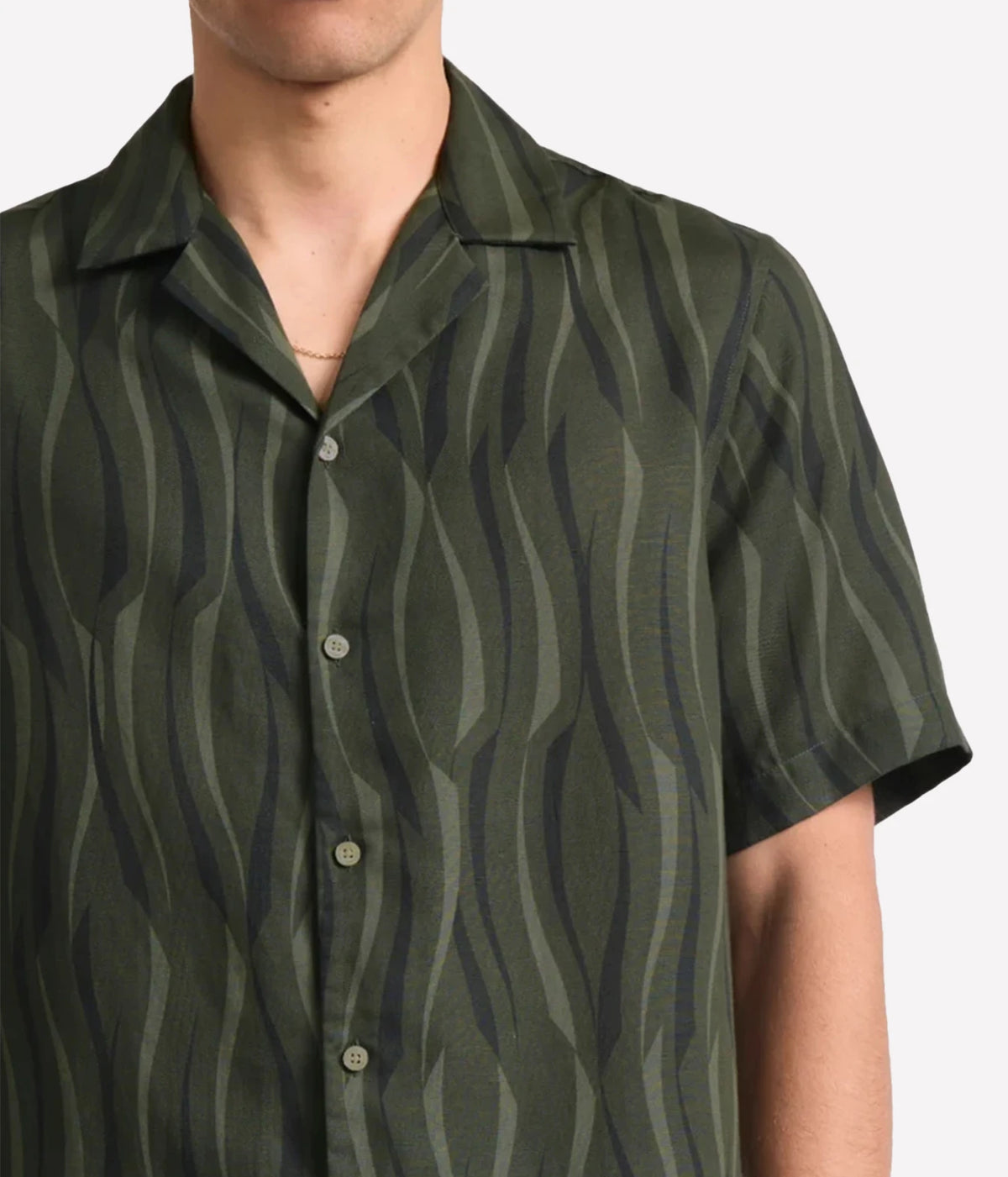 A close-up of a man wearing a Frescobol Carioca Roberto Short Sleeve Linen-Blend Shirt in Cove Green, set against a plain light grey background.
