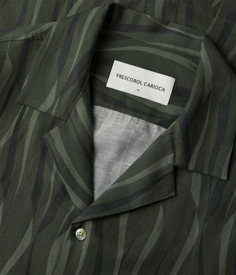 Close-up of a Frescobol Carioca Roberto Short Sleeve Linen-Blend Shirt in Cove Green, featuring a dark olive green and  black wavy stripe pattern with a white brand label visible inside the collar.