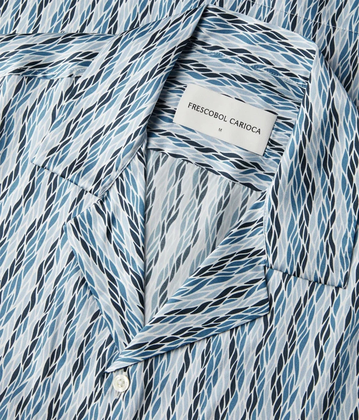 Close-up of a patterned button-up shirt collar with a white neck label reading 'FRESCOBOL CARIOCA'. The fabric has a diagonal wavy stripe pattern in shades of blue, navy, and black on a white base.