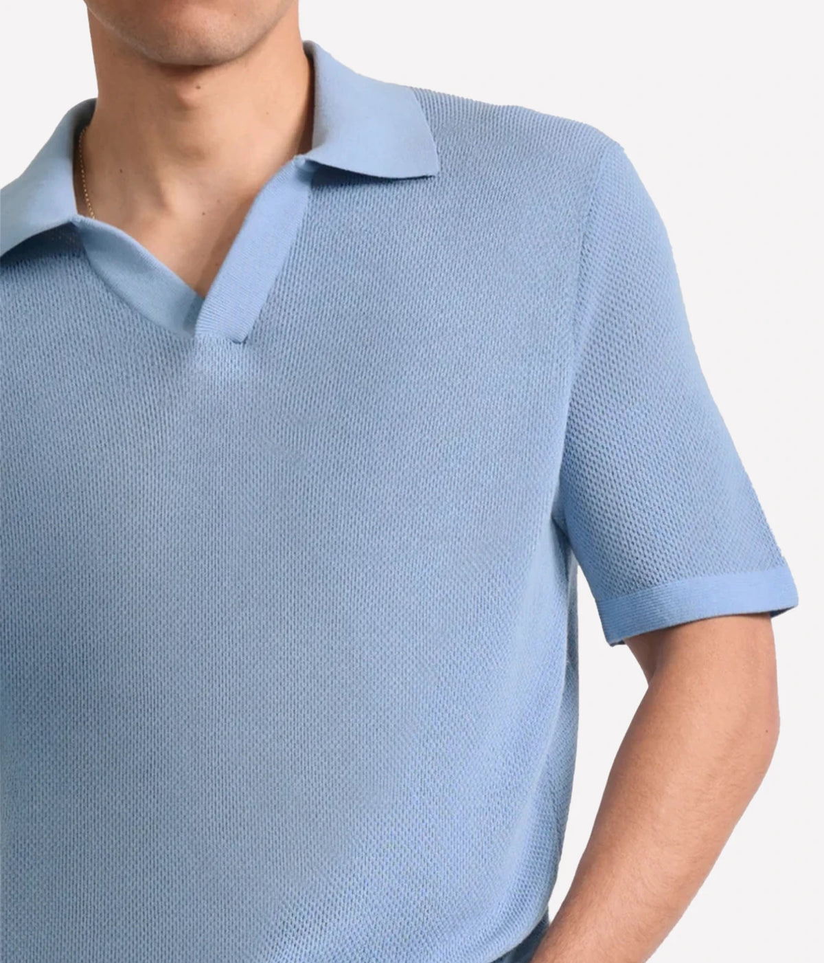 A close-up of a man wearing a Frescobol Carioca Rino Short Sleeve Cotton Polo in Light Denim Blue against a plain light background.