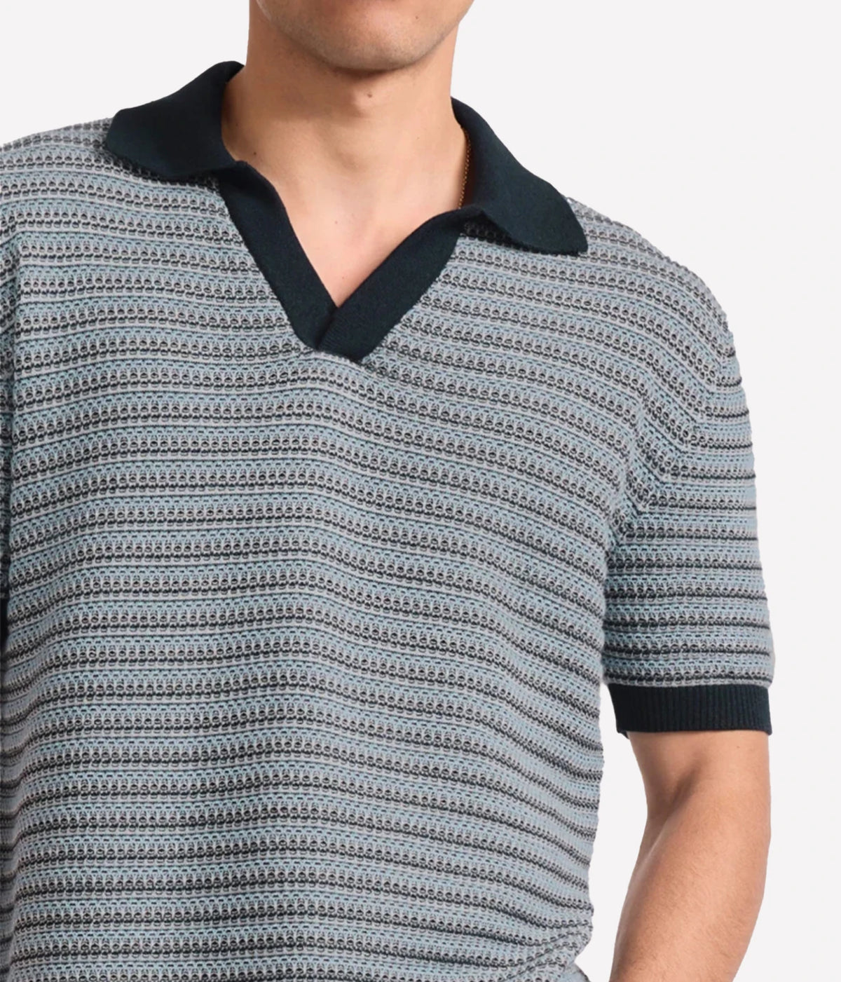 A close-up of a man wearing Frescobol Carioca Rino Short Sleeve Cotton Polo in Navy with a textured navy, grey and white horizontal stripe pattern, featuring a solid navy collar and sleeve cuffs.