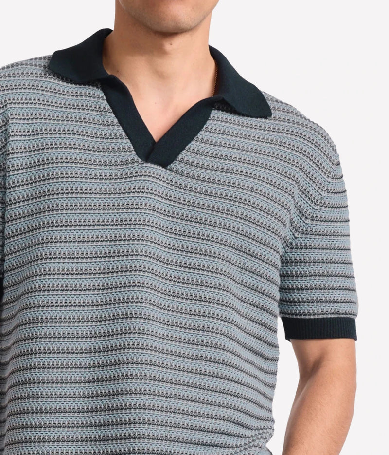 A close-up of a man wearing Frescobol Carioca Rino Short Sleeve Cotton Polo in Navy with a textured navy, grey and white horizontal stripe pattern, featuring a solid navy collar and sleeve cuffs.
