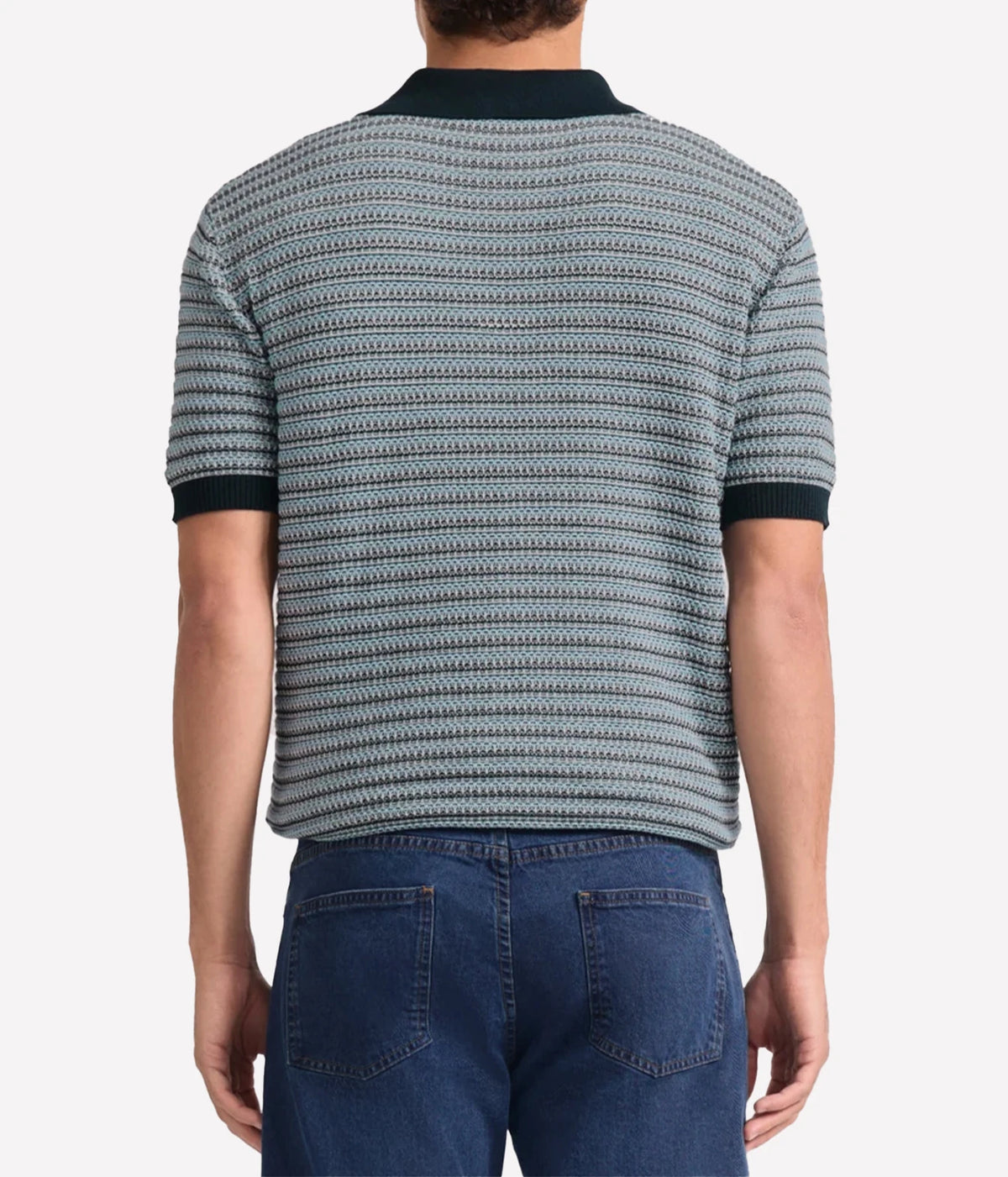 A man viewed from the back wearing a Frescobol Carioca Rino Short Sleeve Cotton Polo in Navy with a navy, grey and white textured pattern and dark navy collar and sleeve cuffs, paired with blue jeans.