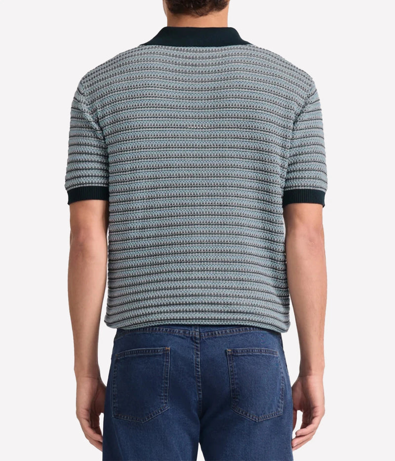A man viewed from the back wearing a Frescobol Carioca Rino Short Sleeve Cotton Polo in Navy with a navy, grey and white textured pattern and dark navy collar and sleeve cuffs, paired with blue jeans.