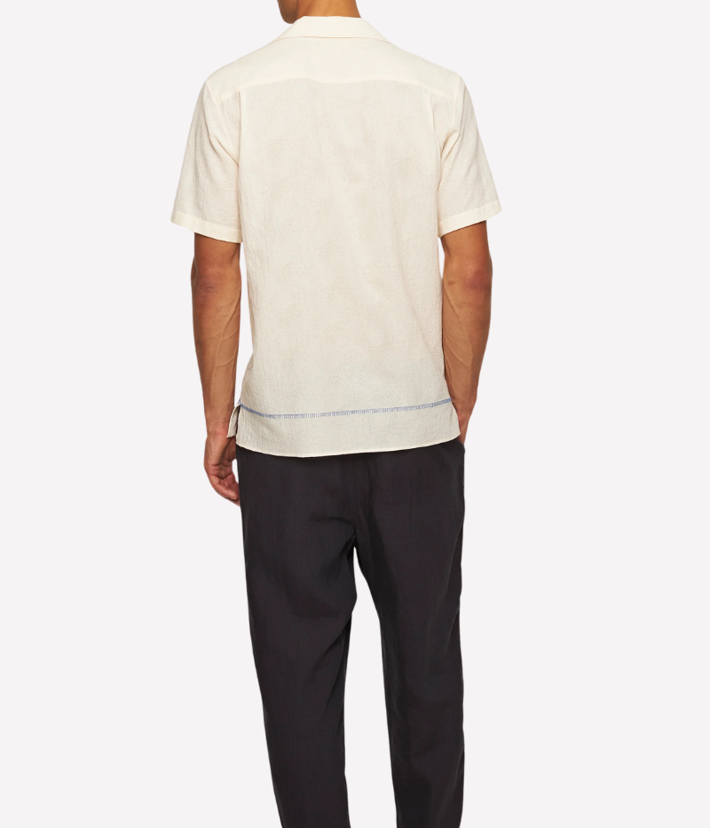 White Sands Orlebar Brown Maitan Anthinos Shirt with Capri collar, concealed button placket, and intricate blue Grecian-inspired embroidery along the placket and hem. Made from lightweight Italian-woven cotton with side hem splits and imitation mother-of-pearl buttons