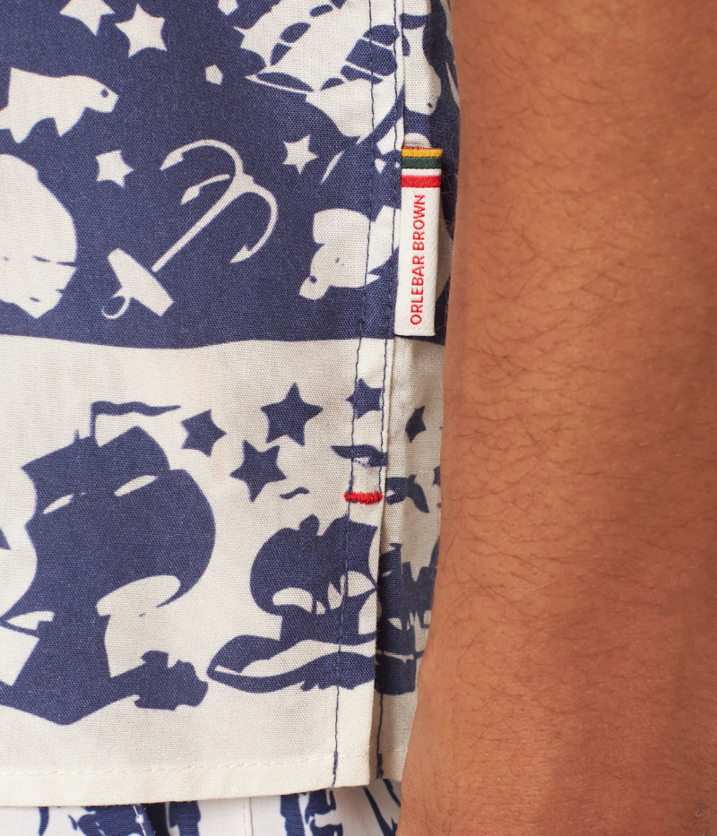 Orlebar Brown Maitan Shirt featuring an artistic maritime print with shells, seagulls, sailboats, and marine life. The short-sleeved shirt includes a Capri collar, hidden button placket, and slit hem for a clean silhouette. Made from 100% Lyocell, machine washable at 30°C.