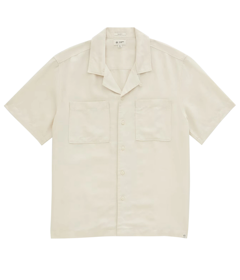 A short-sleeve camp collar button-up shirt in cream-colored cotton, featuring two chest pockets and a button-down front, laid flat against a white background.