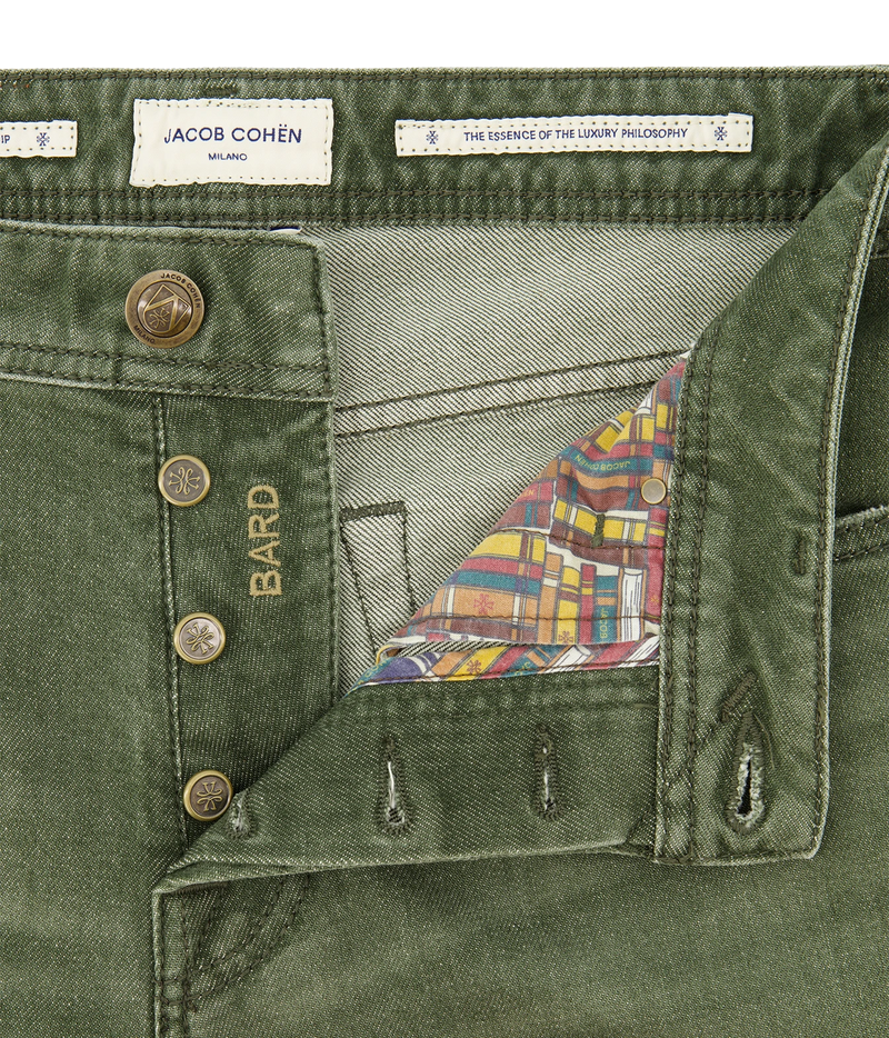 Close-up of olive green denim shorts by Jacob Cohén, showing the waistband, button closure, and a colorful plaid lining visible inside the waistband.