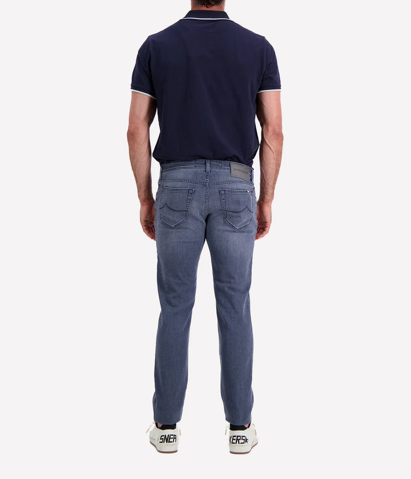Jacob Cohen Bard 5 Pocket Slim Jeans in a washed blue finish, featuring a modern slim fit, classic five-pocket styling, and contrast stitching. Styled with a navy tee and white sneakers for a casual yet polished look.