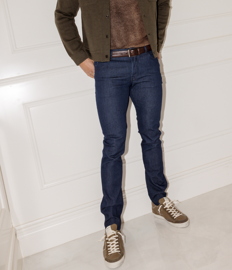 Person wearing a green jacket, brown shirt, blue jeans, and brown shoes on a white background