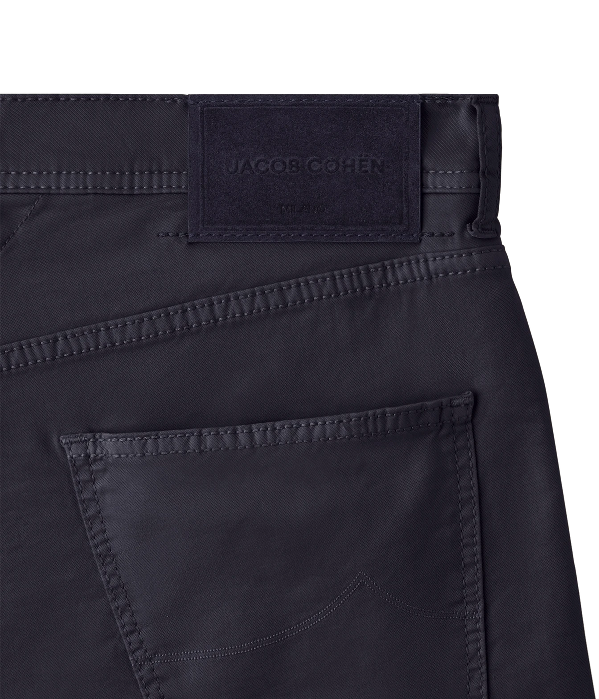 Close-up of the waistband and back pocket of dark navy blue jeans, showing a stitched Jacquob Cohen label at the back waist.