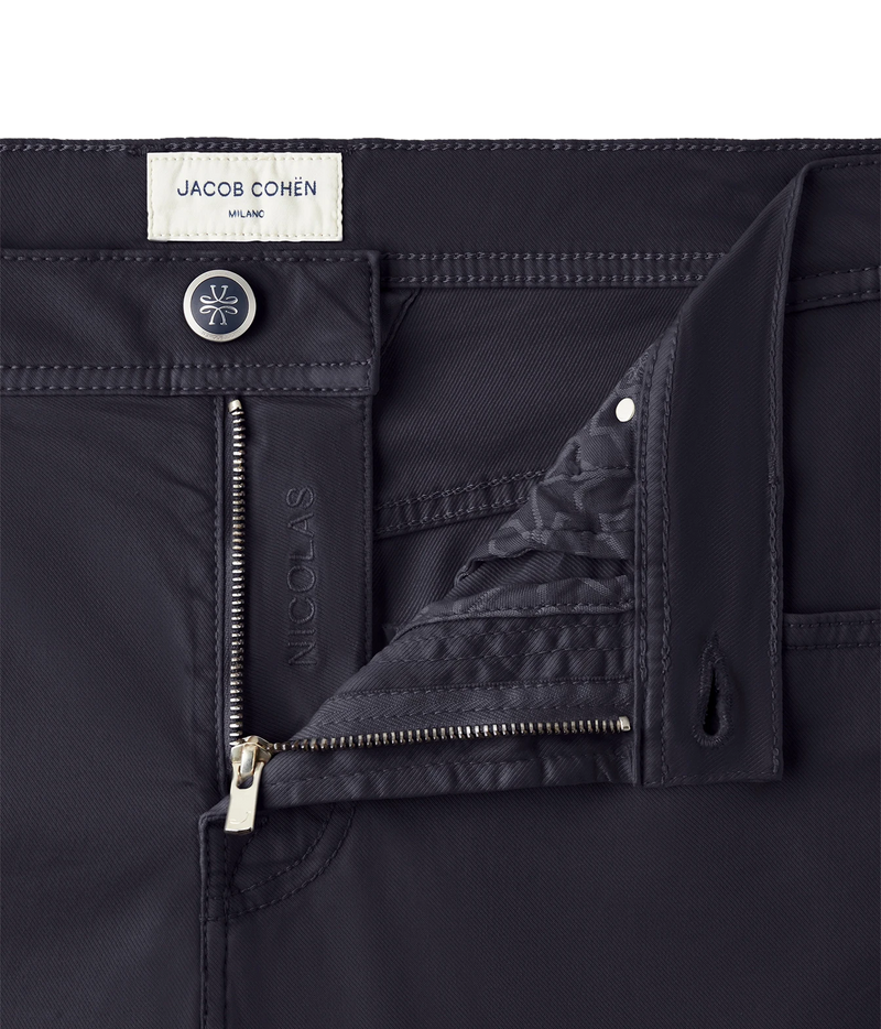 Close-up of dark navy pants by Jacob Cohen, showing the waistband, button closure, front zip, and a folded pocket revealing a quilted lining.