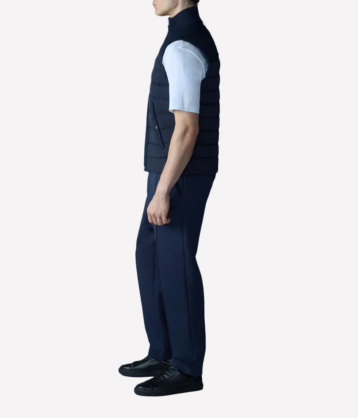 Quilted down vest with stretch nylon and twill panels, ribbed collar, and snap-secured pockets, designed for lightweight warmth and layering.