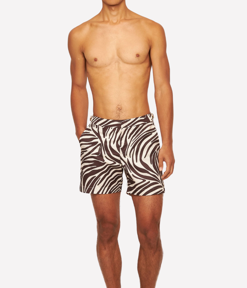 Model wearing the Orlebar Brown Bulldog Golden Gun Zebra Swim Shorts in Truffle Latte, paired with a linen shirt for effortless, refined poolside style with a Bond-inspired twist.