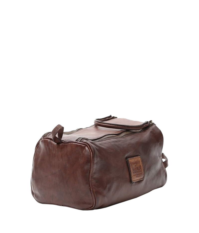 Three-quarter view of Campomaggi Leather Toiletries Bag in Brown showing the leather logo tab