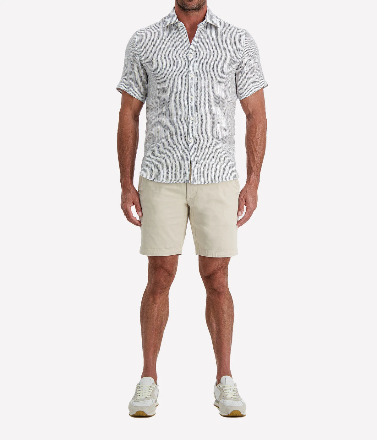 Man wearing Osvaldo Trucchi Linen Short Sleeve Shirt in Navy Woven Stripe with stone shorts and white sneakers, full-length front view