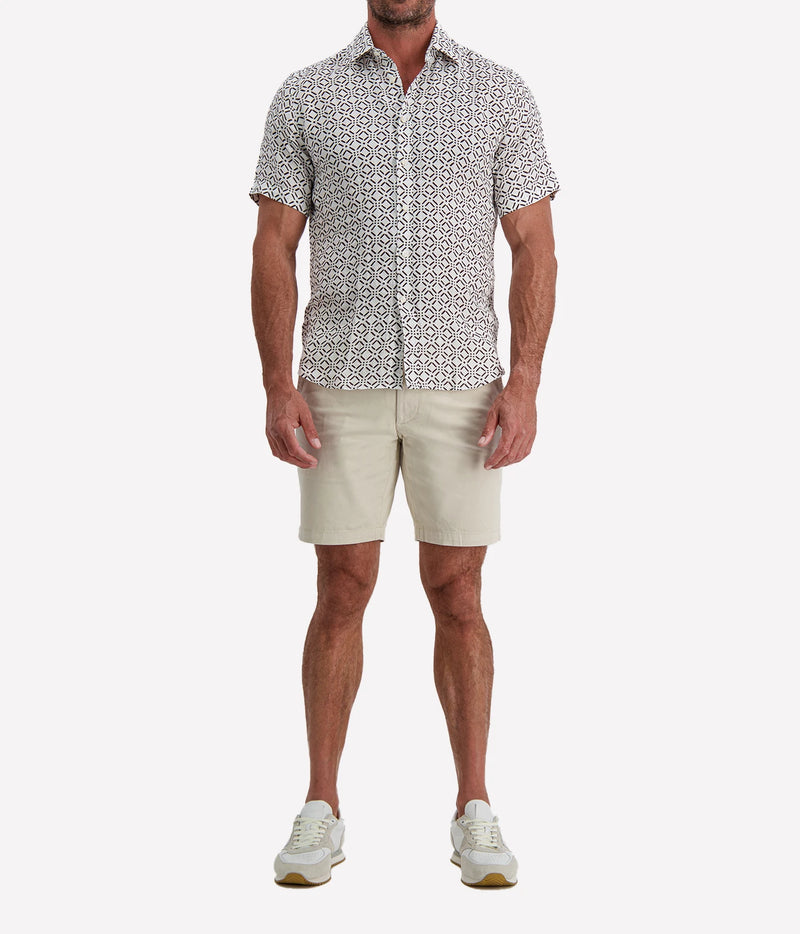Man wearing Osvaldo Trucchi Linen Short Sleeve Shirt in Brown Geo Diamond Print with stone shorts and white sneakers, full-length front view