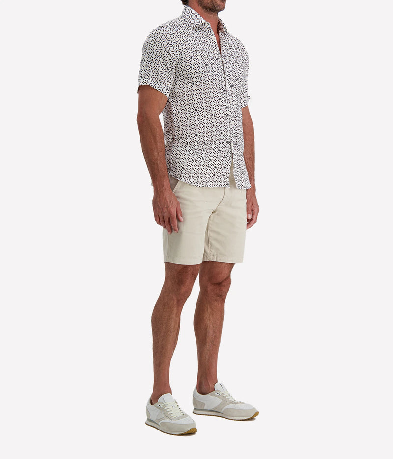 Man wearing Osvaldo Trucchi Linen Short Sleeve Shirt in Brown Geo Diamond Print with stone shorts and white sneakers, front view