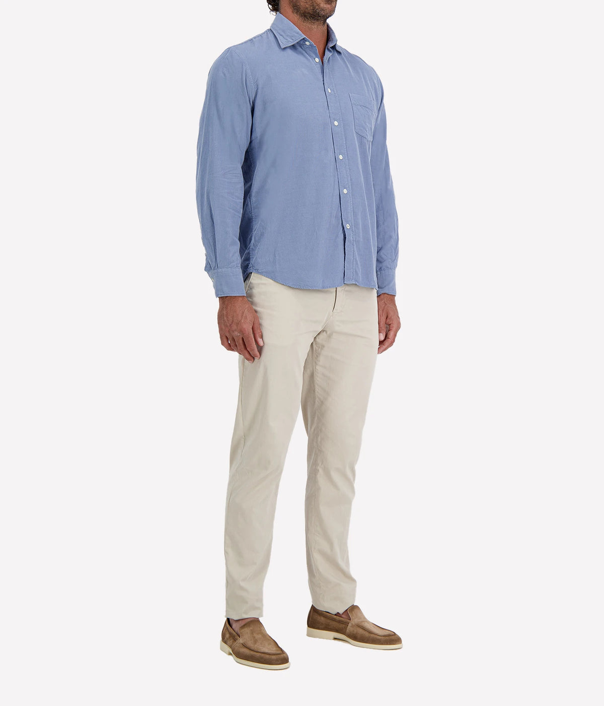 Man wearing Hartford Paul Fine Corduroy Shirt in Chambray Blue with stone chinos and brown suede shoes, three-quarter view