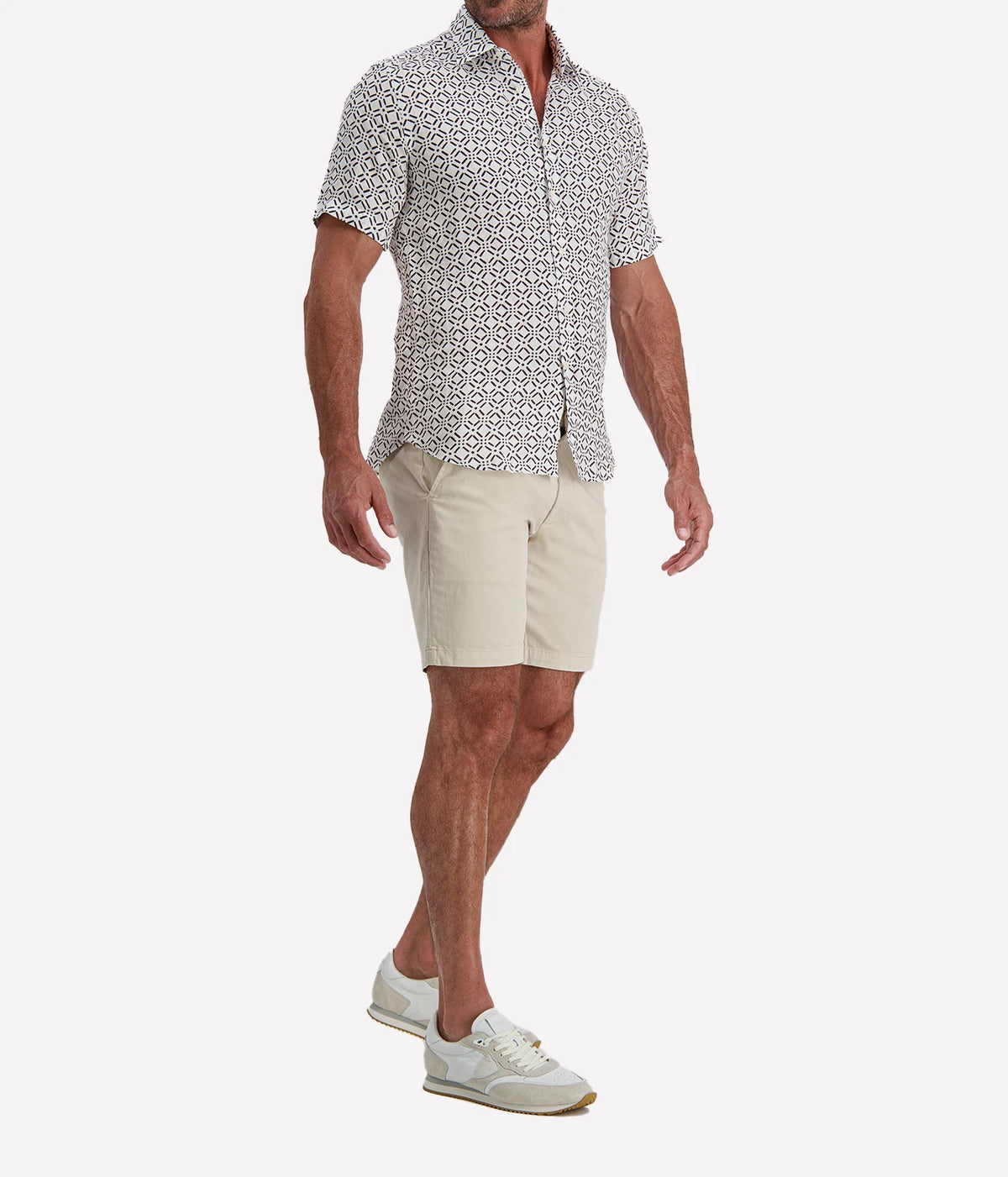 Man wearing Osvaldo Trucchi Linen Short Sleeve Shirt in Brown Geo Diamond Print with stone shorts and white sneakers, three-quarter view