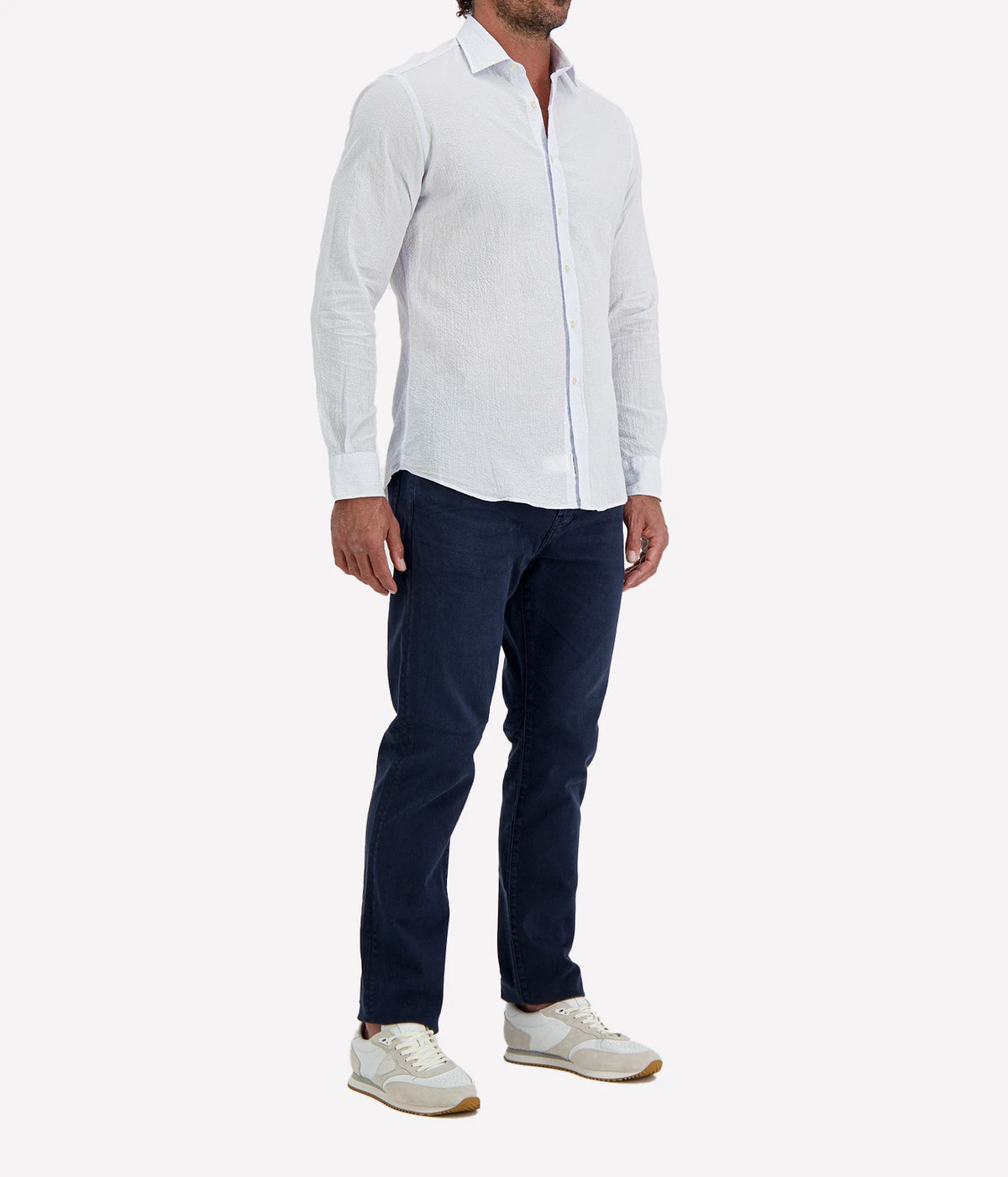 Man wearing Ingram Slim Fit Shirt in Seersucker Blue & White Stripe with indigo jeans and white sneakers, angled front view