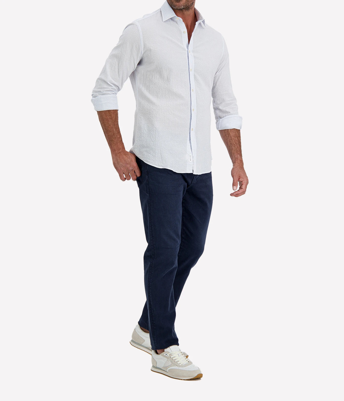 Man wearing Ingram Slim Fit Shirt in Seersucker Blue & White Stripe with indigo jeans and white sneakers, three-quarter view