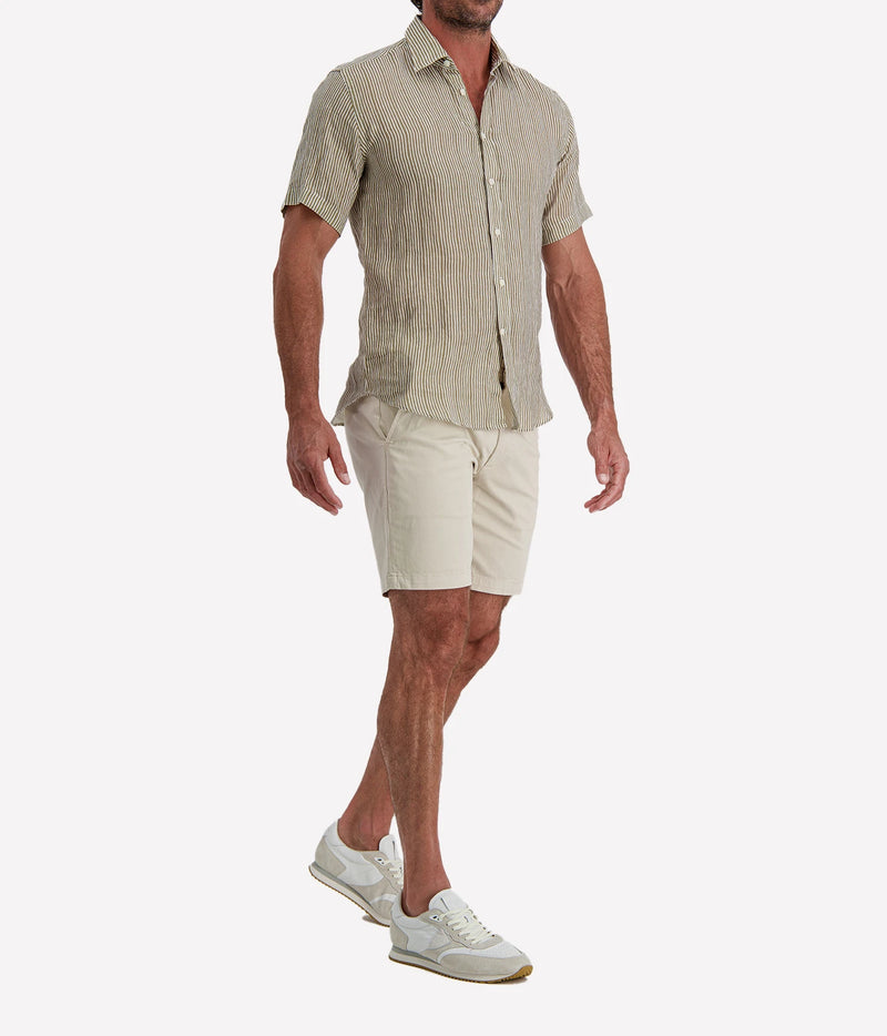 Man wearing Osvaldo Trucchi Linen Short Sleeve Shirt in Olive and White Stripe with stone shorts and white sneakers, three-quarter view