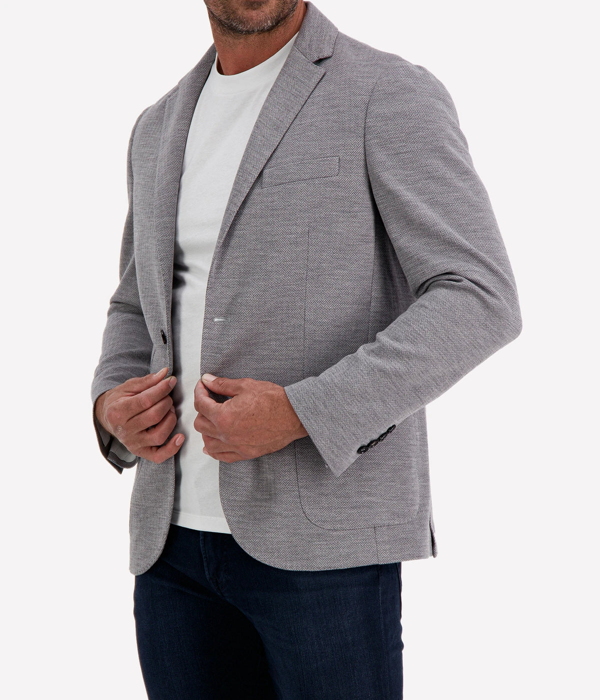 Man wearing Maurizio Baldassari Brera 6pm Herringbone Wool Jacket in Grey with a white T-shirt and dark jeans, cropped angled front view