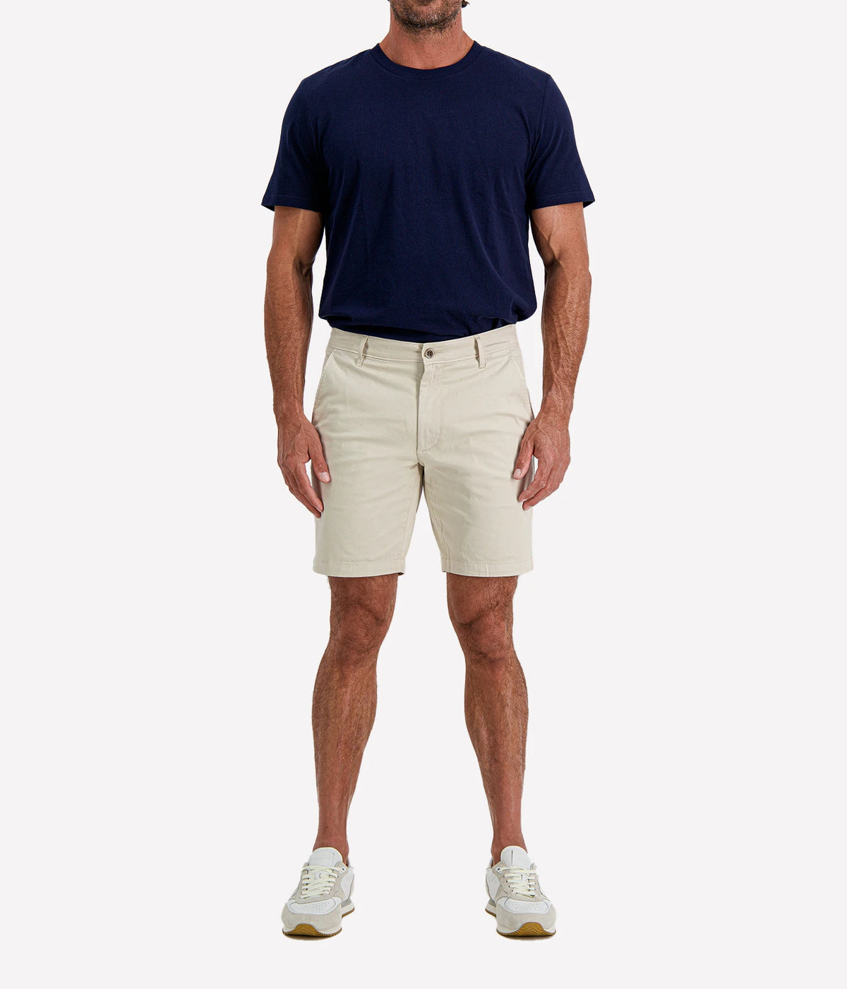Man wearing AG Wanderer Short in Pumice with a navy T-shirt and white sneakers, full-length front view