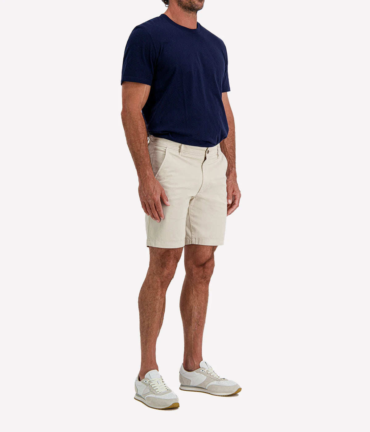 Man wearing AG Wanderer Short in Pumice with a navy T-shirt and white sneakers, side view