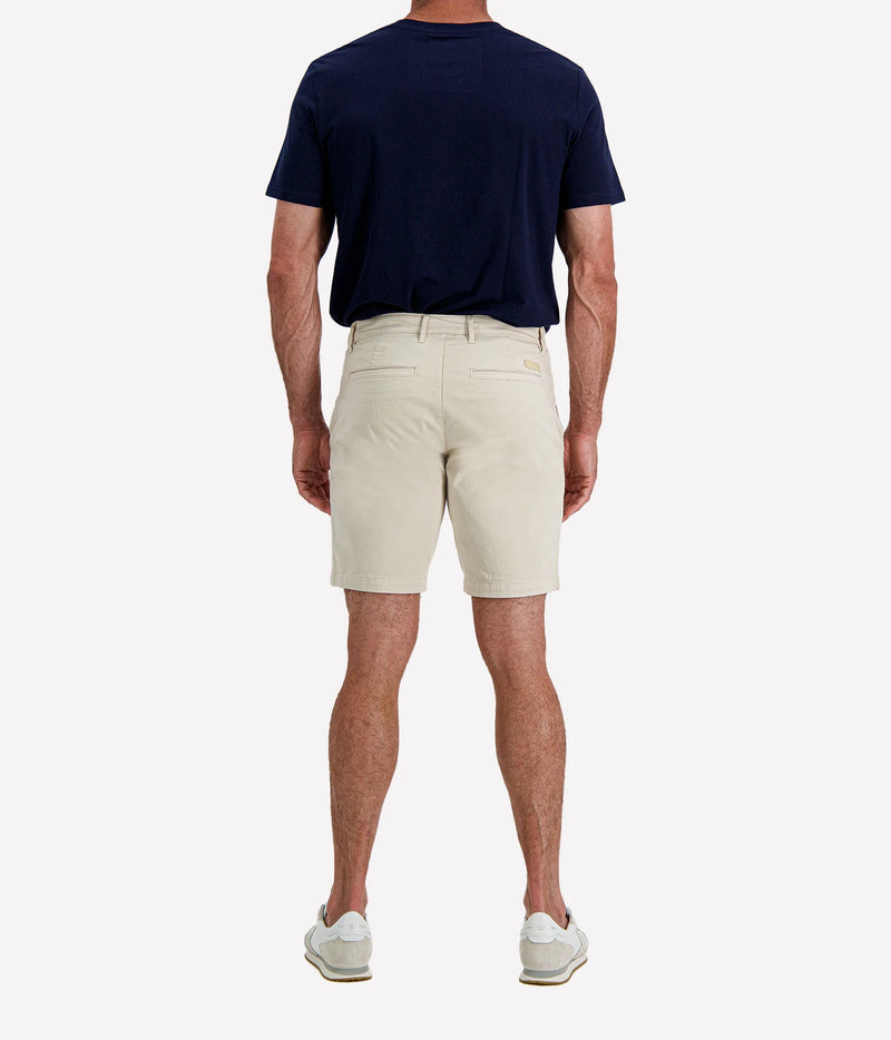 Man wearing AG Wanderer Short in Pumice with a navy T-shirt and white sneakers, front view