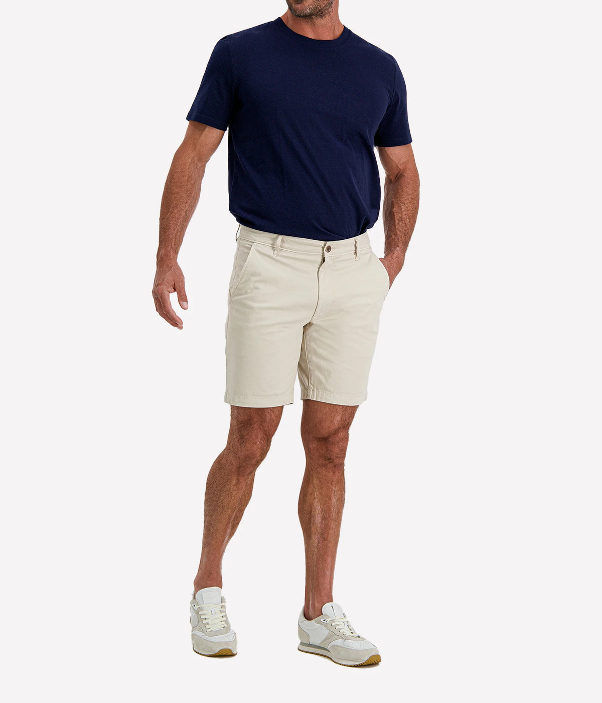 Man wearing AG Wanderer Short in Pumice with a navy T-shirt and white sneakers, three-quarter view
