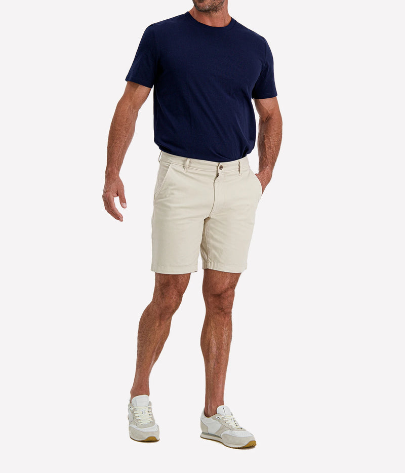 Man wearing AG Wanderer Short in Pumice with a navy T-shirt and white sneakers, three-quarter view