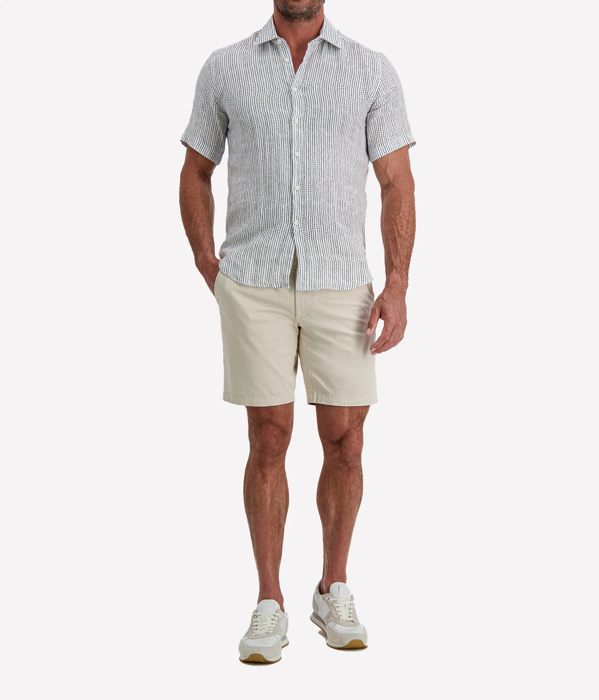 Man wearing Osvaldo Trucchi Linen Short Sleeve Shirt in Navy Woven Stripe with stone shorts and white sneakers, front view