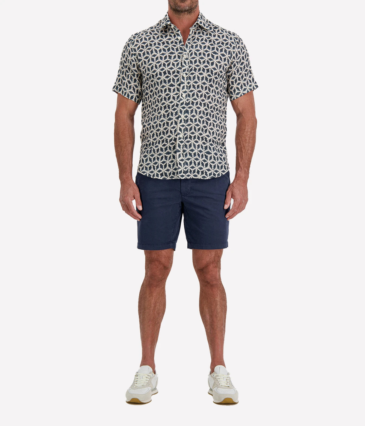 Man wearing Osvaldo Trucchi Linen Short Sleeve Shirt in Navy Geo Star Print with navy shorts and white sneakers, full-length front view